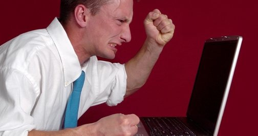 Angry guy making fist at computer