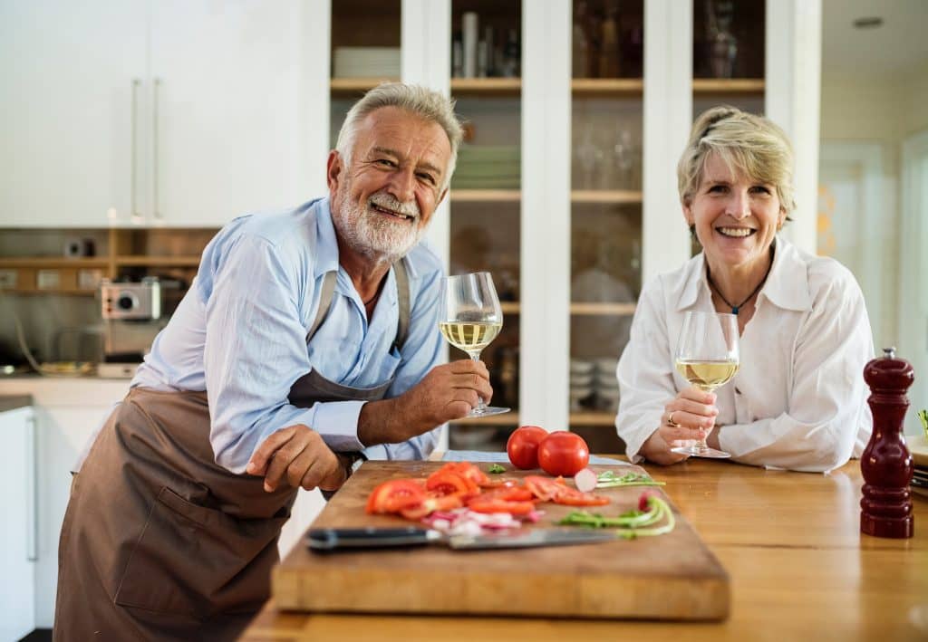 Elderly couple drinking wine at a kitchen island.