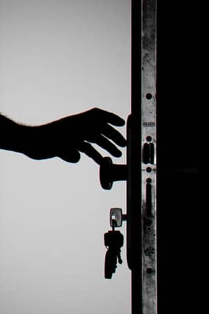 person-reaching-for-doorknob-with-keys-in-door