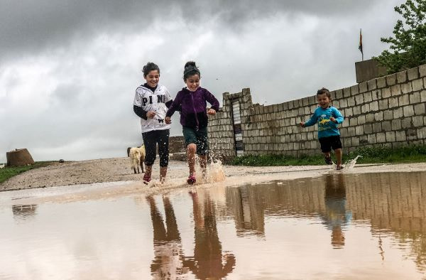 Kids smiling and jumping in puddles